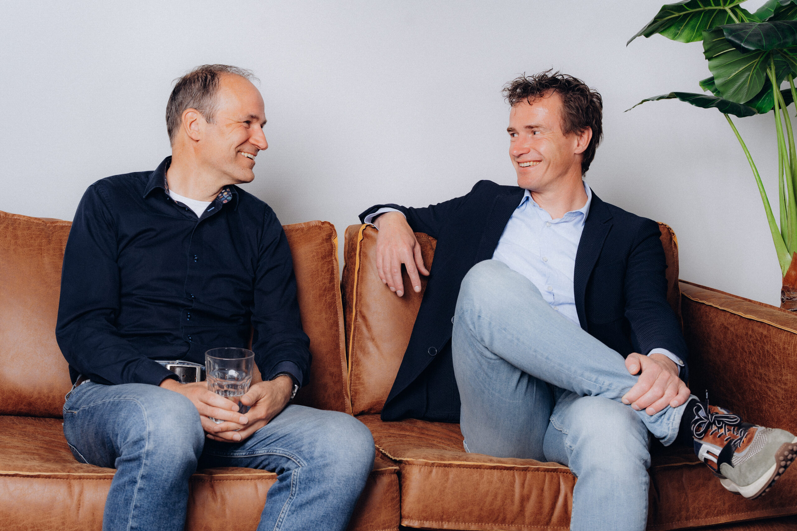 Lachende collega's van Midglas zittend op een bank