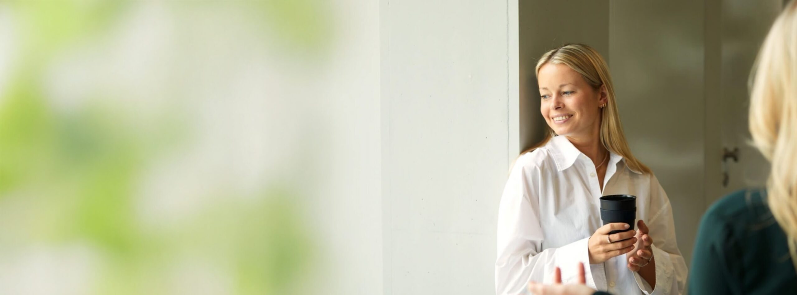 Lachende dame met een kop koffie leunend tegen de muur