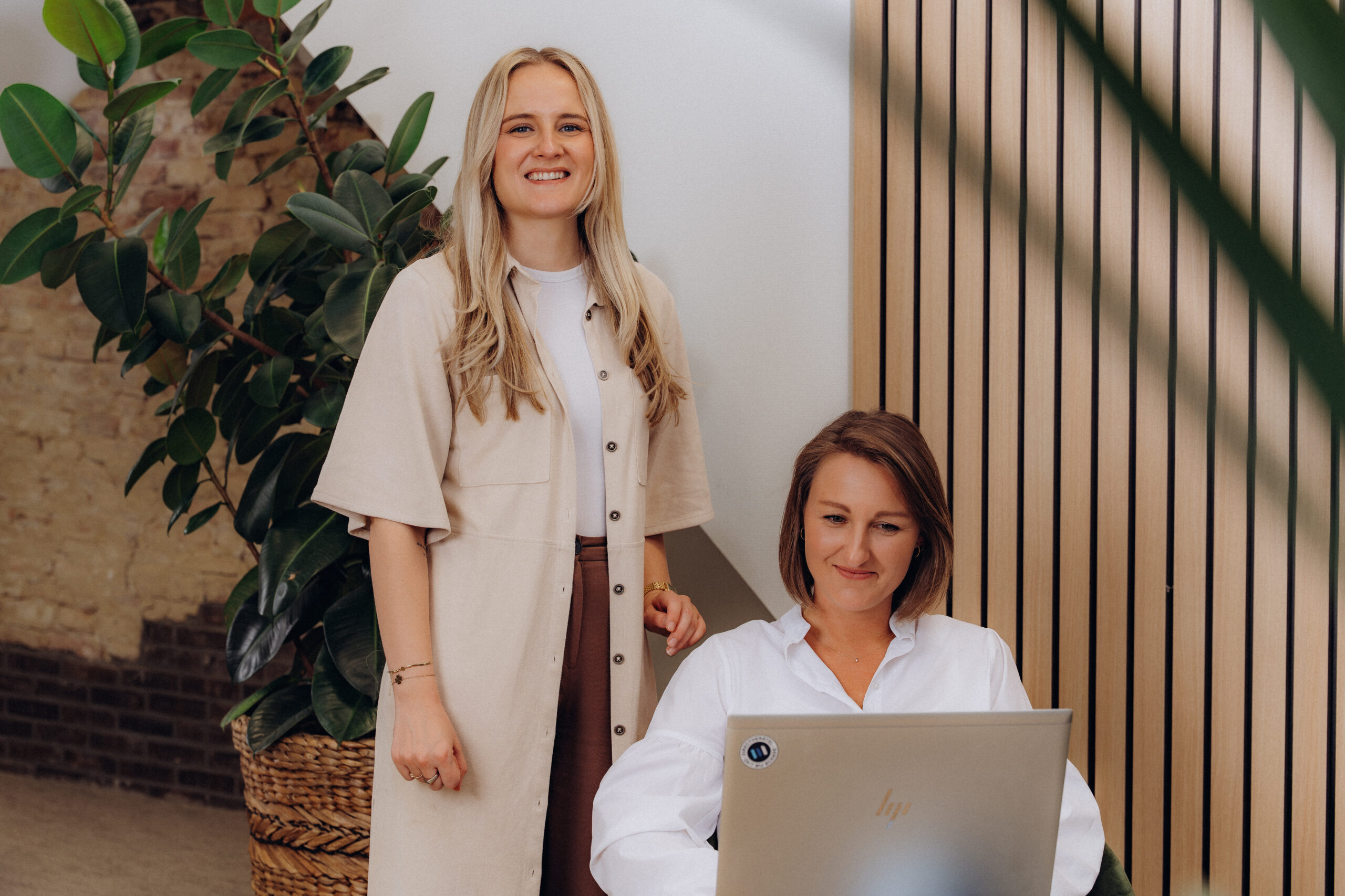 Twee vrouwelijke Midglas collega's lachend en kijkend naar de camera